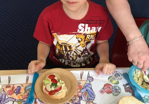 chłopiec siedzi przy stoliku z wielkanocnymi potrawami